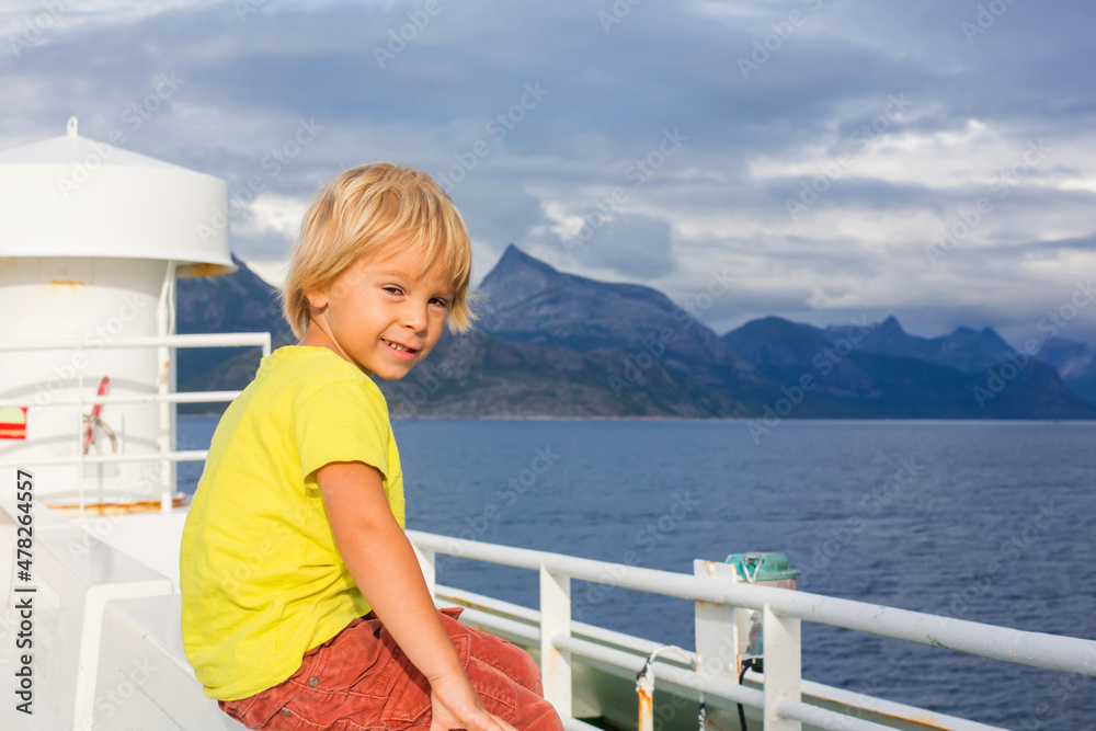 Child, cute boy, looking at the mountains from a ferry in Nortern Norway