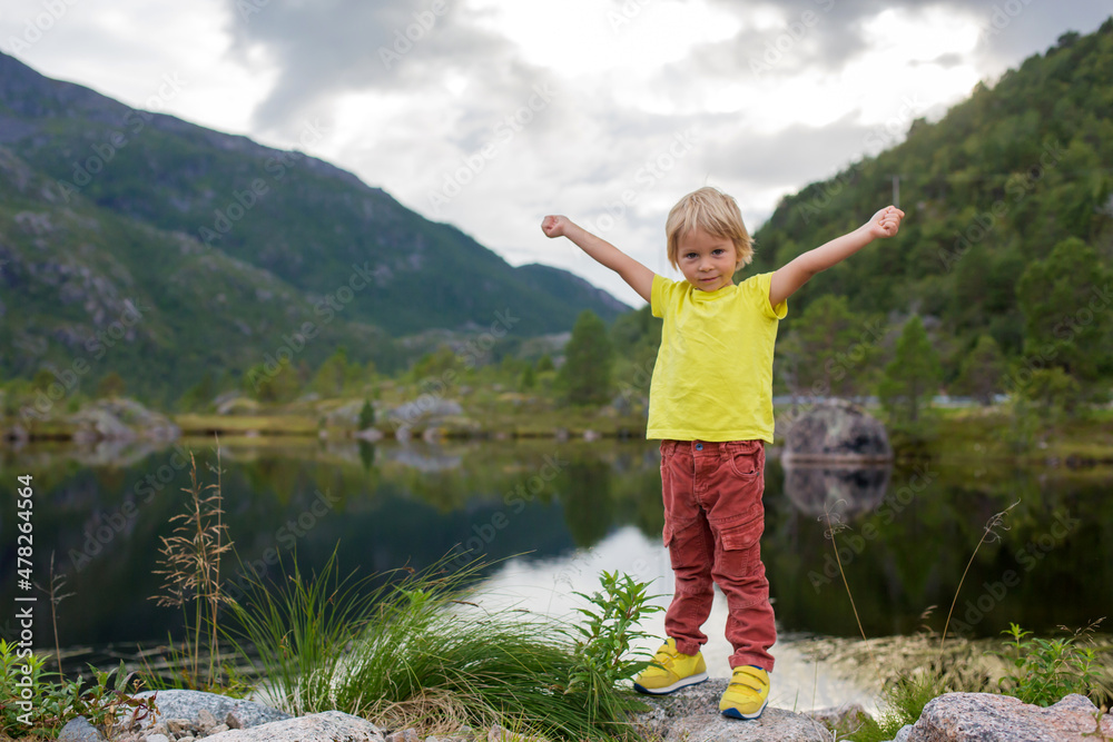 Beautiful blond child, cute boy, standing on the edge of a fjord in Lofoten