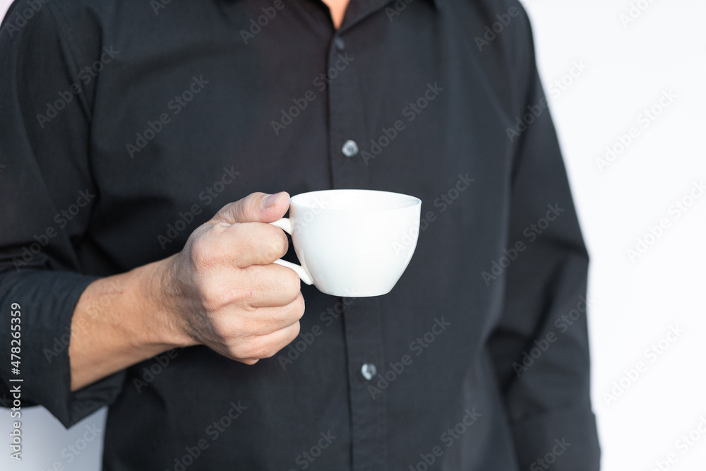 Closeup portrait of handsome smart business man is holding white coffee cup with black shirt on isolated white background. Closeup portrait of handsome smart business man is holding white coffee cup with black shirt on isolated white background.