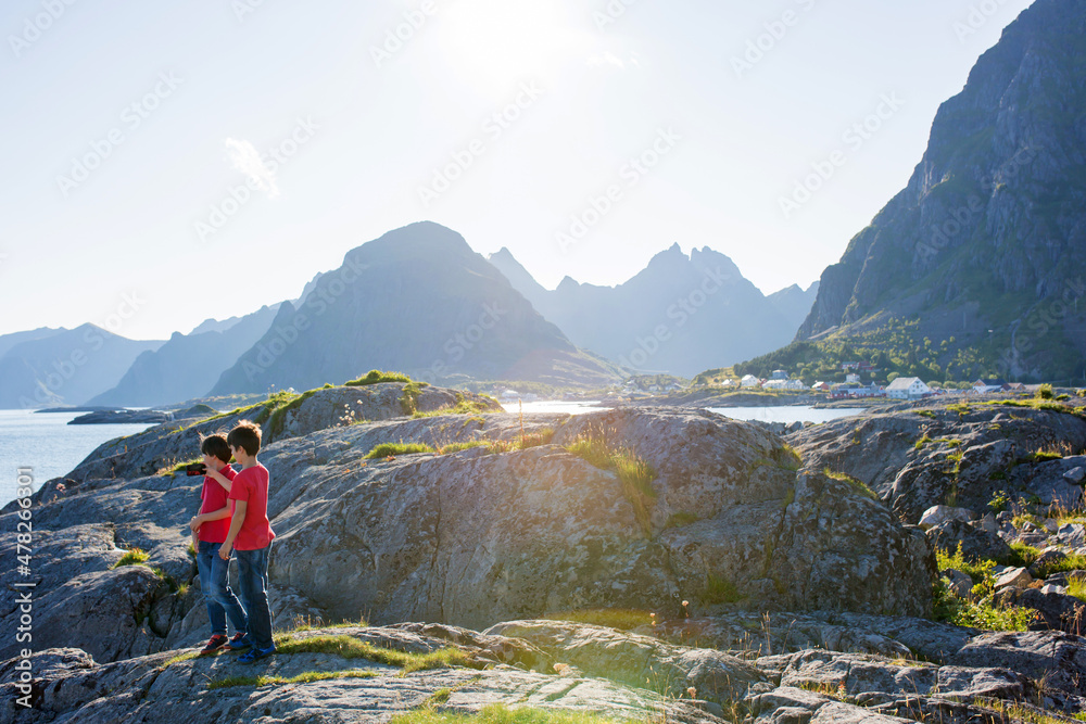 Fototapeta premium Happy family, enjoying the pier in Sorvagen, Lofoten island, Norway. Children, running on a sunny day on the rocks, enjoying