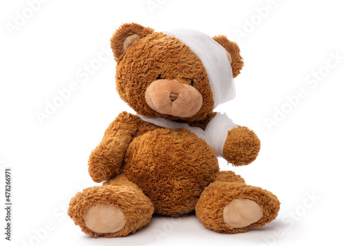 medicine, healthcare and childhood concept - teddy bear toy with bandaged head and paw on white background