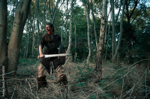 Angry female viking with weapon and shield during battle reconstruction