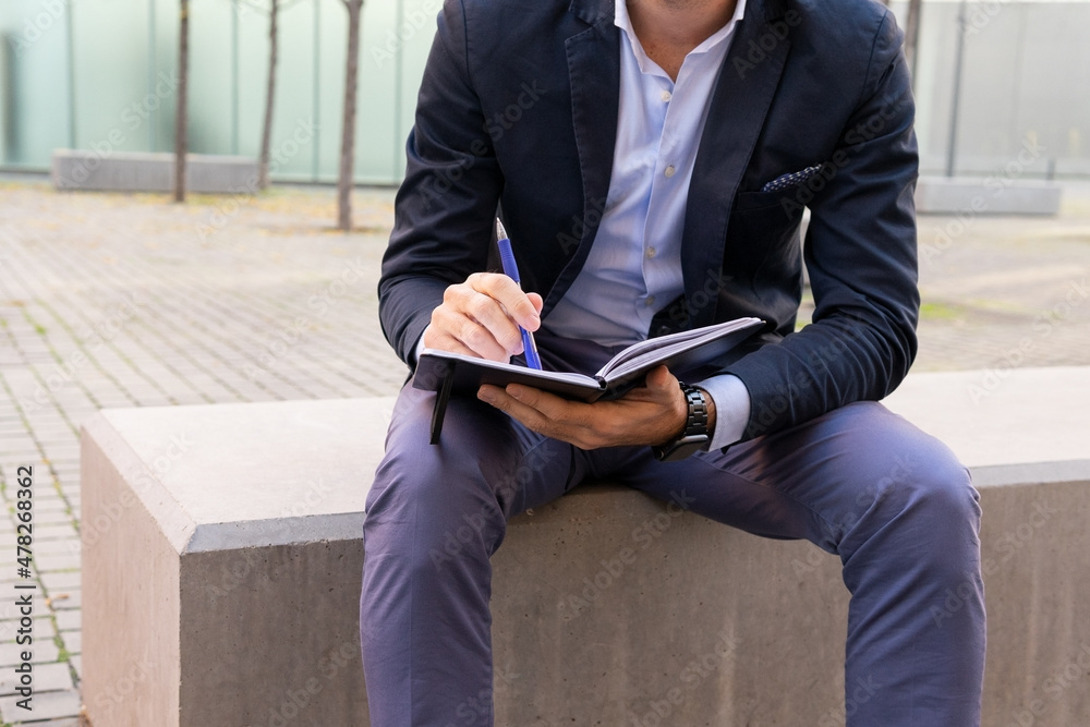 Unrecognizable businessman writing in notebook on street Unrecognizable businessman writing in notebook on street