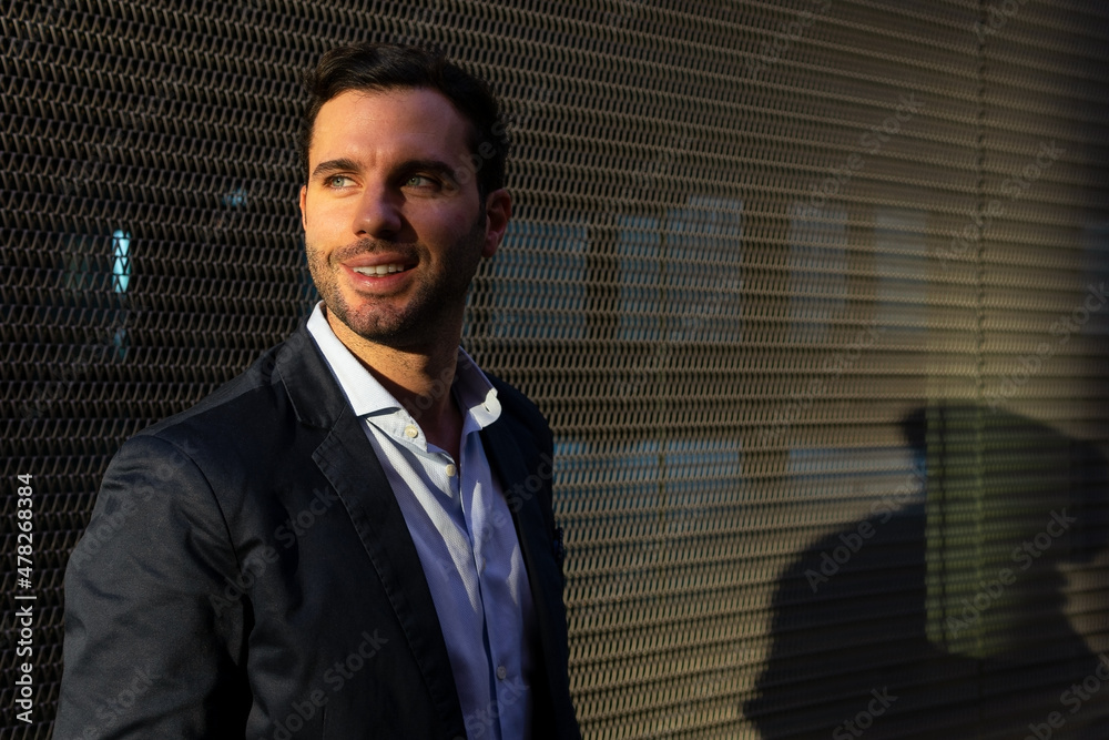 Businessman near wall on sunny street