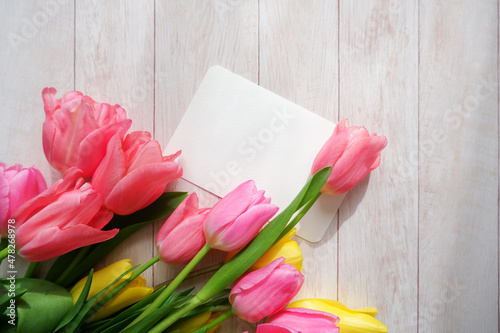 Fototapeta Naklejka Na Ścianę i Meble -  Beautiful color tulip flowers composition with blank card on white wooden table. floral background for Mother's day, Women's day, Easter and Spring time.