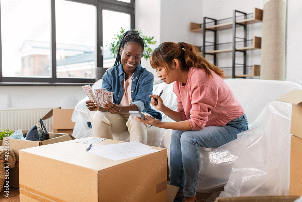 moving, finances and real estate concept - women with money, bills and calculator at new home moving, finances and real estate concept - women with money, bills and calculator at new home