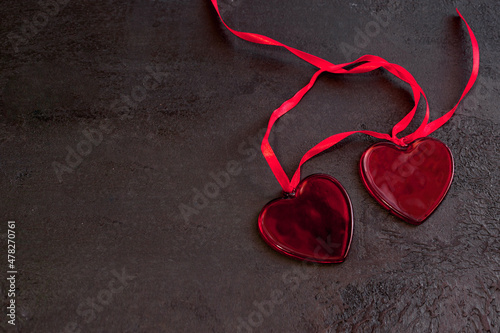 Top view of two red hearts with ribbon on dark texture background for Valentines day celebration or love concept