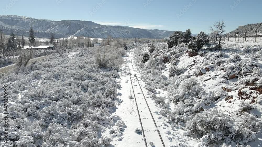 Flying along unused train tracks with fresh snow and rising to see part of Interstate 70. Filmed in the Rocky Mountains of Colorado between Eagle and Avon along Interstate 70.