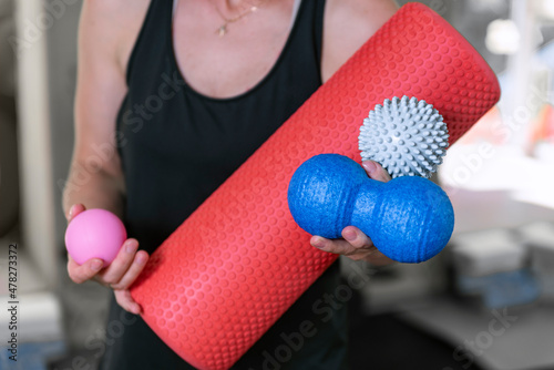 Young athletic woman holds equipment for MFR. Myofascial massage trainer. Different types myofascial rolls. Close up photo