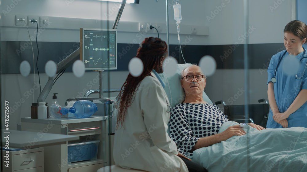 Nurse and african american doctor tending to ill patient in hospital ...