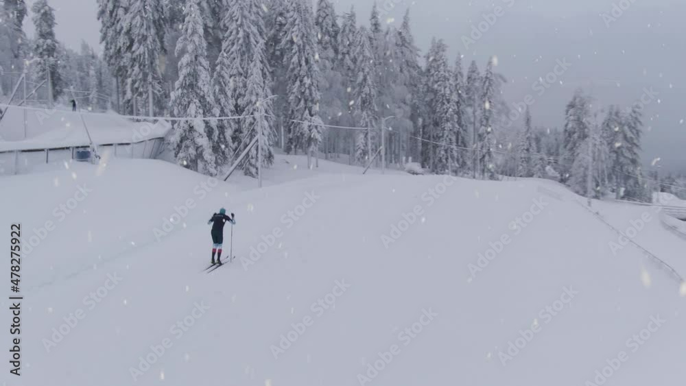 Athlete preparing for winter Olympics in cross country skiing during snowfall, aerial drone shot Athlete preparing for winter Olympics in cross country skiing during snowfall, aerial drone shot