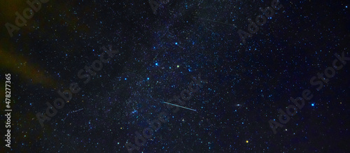 Panorama of the starry sky at night with a shooting star against the background of many galaxies and universes