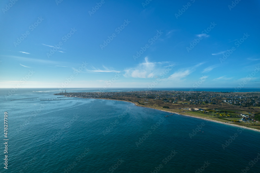 Aerial view of a french city on the atlantic ocean. Water edge on the beach. Blue sky for copy space. France, Brittany, Penmarch.