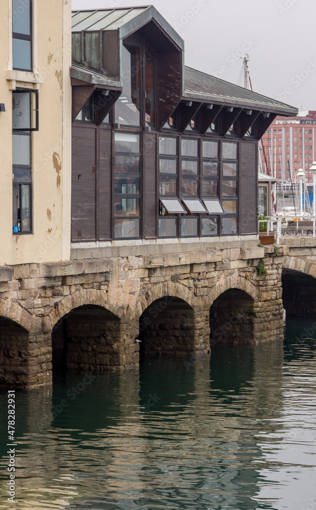 Old arches of stone at the port of Gijon, Spain