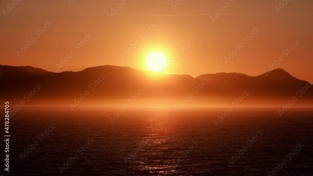 Beautiful golden sunset over the lake. Orange light in front of the mountains. Ketchikan, Alaska is truly the beginning of the Beautiful golden sunset over the lake. Orange light in front of the mountains. Ketchikan, Alaska is truly the beginning of the