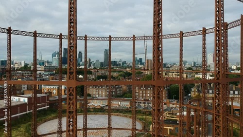 Rusty metal frame of old Victorian gas holder in Bethnal Green, east London. With city of London skyline in background. photo