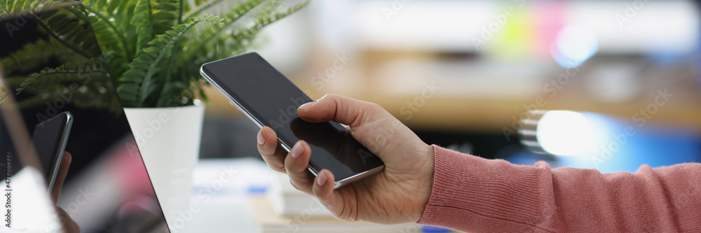 Female hands work on laptop and hold smartphone closeup Female hands work on laptop and hold smartphone closeup