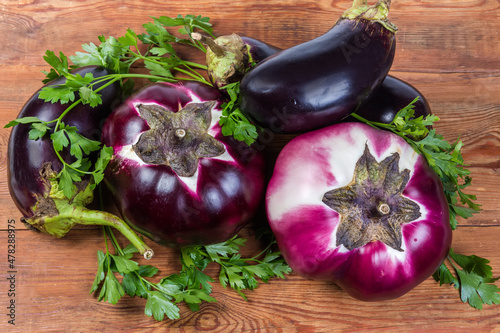 Eggplants two varieties and fresh parsley on old rustic table