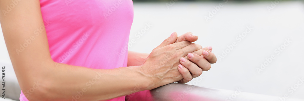 Woman in sportswear with headphones stands with folded arms near river