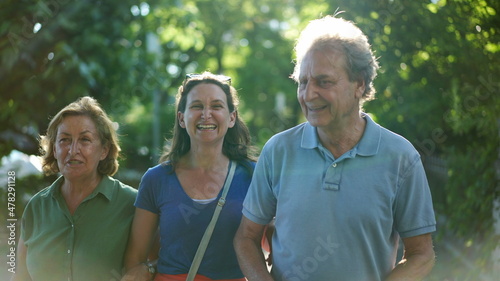 Parents walking with adult daughter together, family day walk outside laughing and smiling