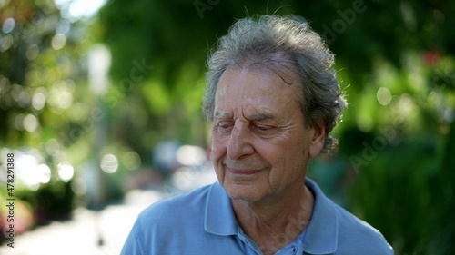 One happy older man walking outside during sunny day, pensive contemplative senior