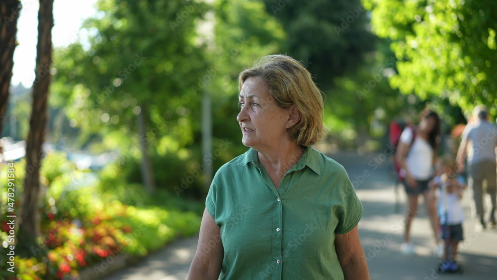 Older woman walking outdoors in green urban city, senior person walks forward outside Older woman walking outdoors in green urban city, senior person walks forward outside