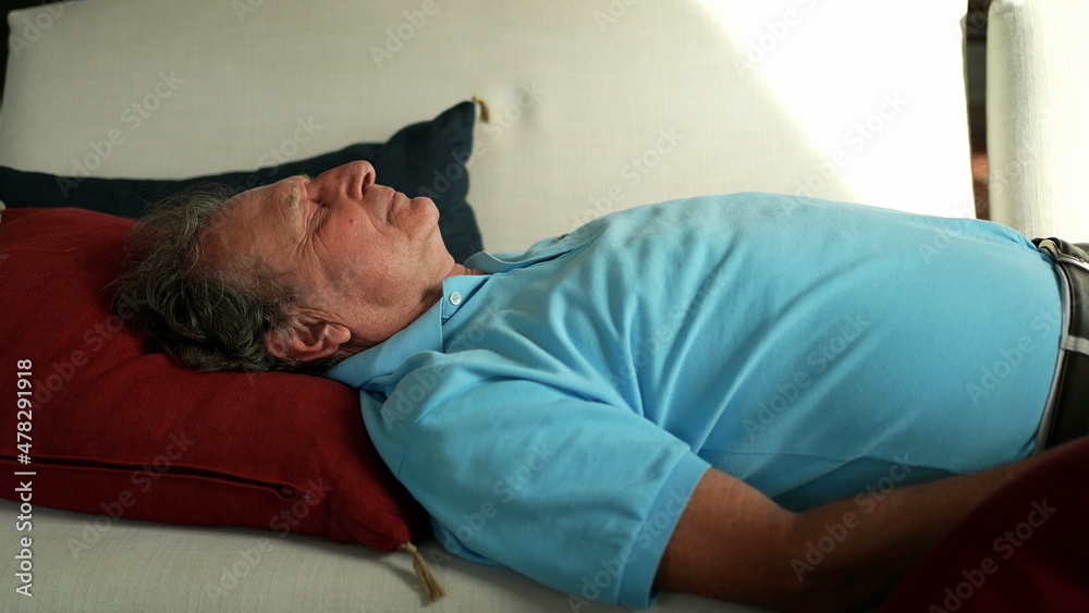 Older man lying in sofa resting. Senior person napping