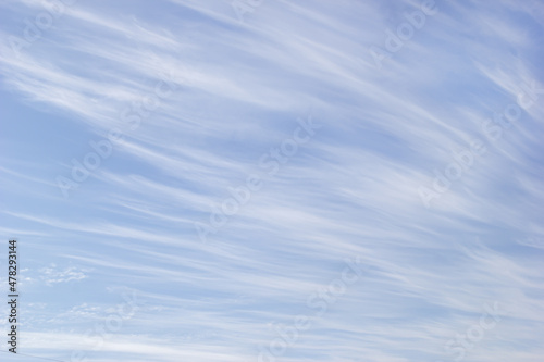 White cirrus clouds on the background blue sky.