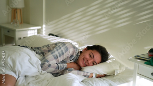 Happy woman lying in bed in the morning smiling relaxing