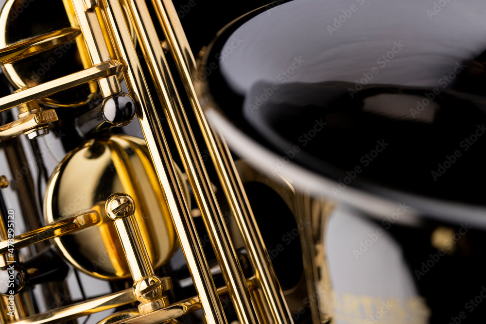Naklejka premium A closeup of a black saxophone with gold plated shiny parts black background