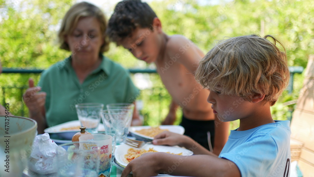 Family eating lunch outside gathered together during meal Family eating lunch outside gathered together during meal