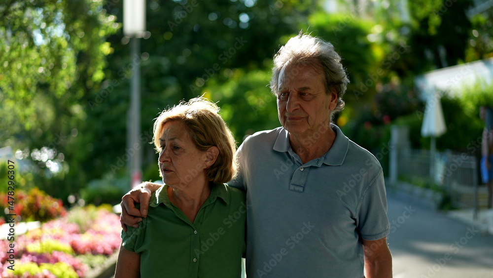 Contemplative seniors walking together outdoors Contemplative seniors walking together outdoors