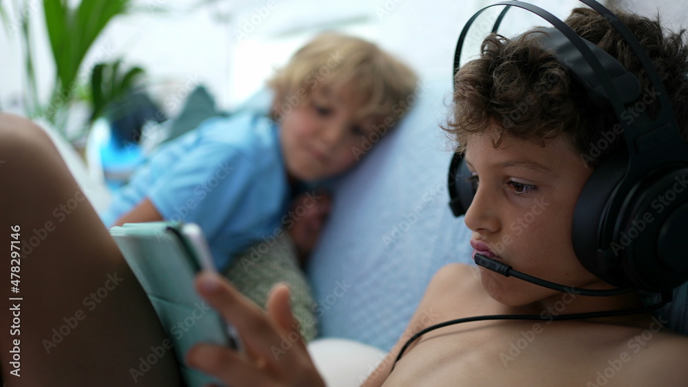 Child plays video-game wearing headset with mic connected online gaming Child plays video-game wearing headset with mic connected online gaming