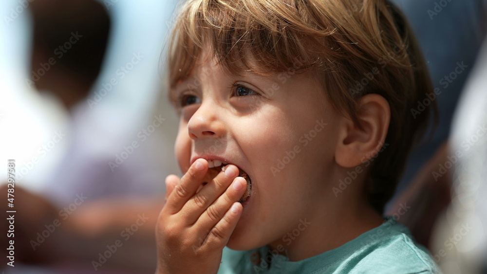 Child eating large piece of bread unable to fit in mouth laughing Child eating large piece of bread unable to fit in mouth laughing
