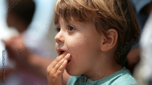 Child eating large piece of bread unable to fit in mouth laughing