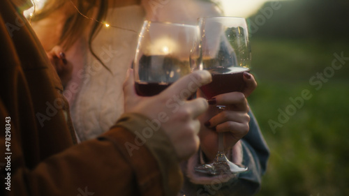 Leinwand Poster Coppia di ragazza e ragazzo bevono vino per san valentino nella natura al tramon