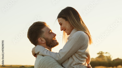 Ragazzo e ragazza si abbracciano e si guardano l'uno con l'altro controluce al tramonto in campagna photo