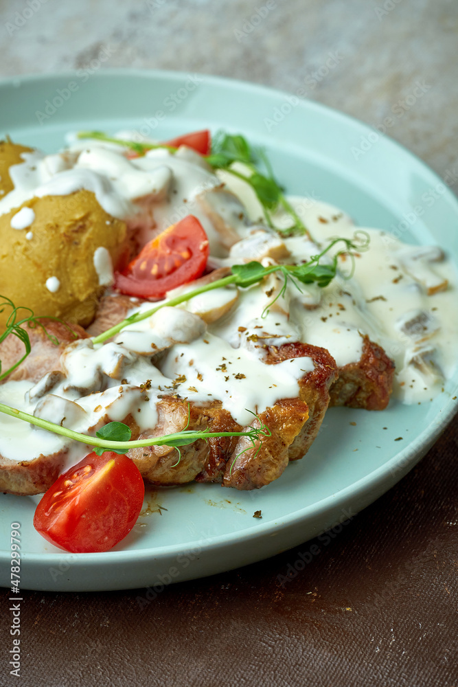 Pork steak with mushroom cream sauce and potatoes in a blue plate on a brown background Pork steak with mushroom cream sauce and potatoes in a blue plate on a brown background
