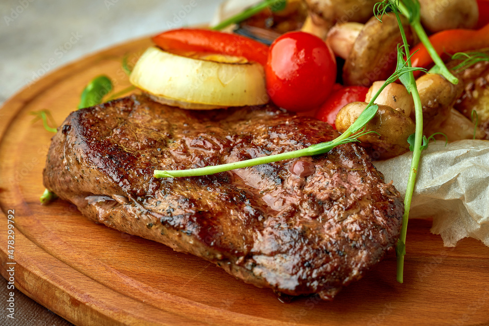 Beef steak with grilled vegetables on a wooden tray
