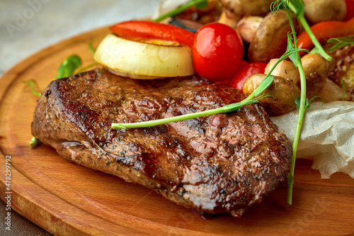 Beef steak with grilled vegetables on a wooden tray