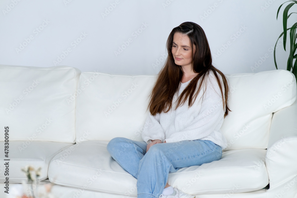 Positive woman in casual clothes sits on comfortable sofa Positive woman in casual clothes sits on comfortable sofa