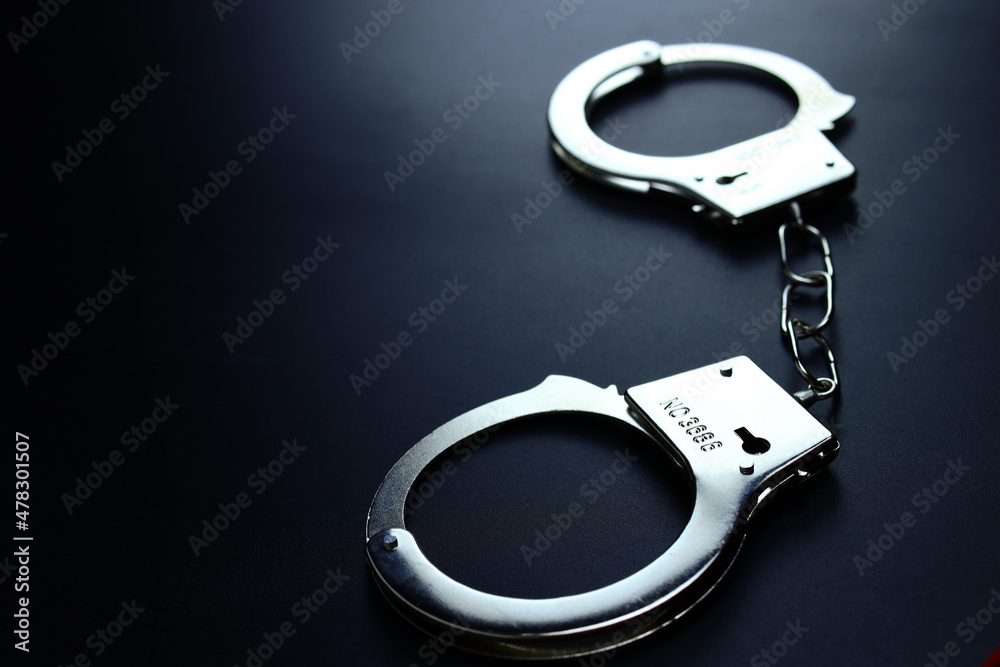 Police metal handcuffs on black background, close-up, selective focus Police metal handcuffs on black background, close-up, selective focus