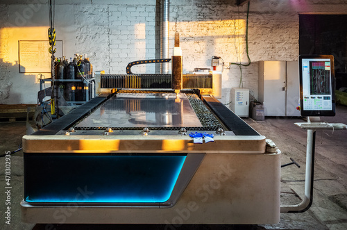 CNC laser cutting machine for sheet metal in a manufacturing facility, illuminated by the morning sun through a window. The picture was taken in Russia, in the workshop of a mechanical plant