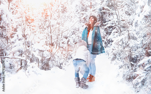 Young family for a walk. Mom and daughter are walking in a winter park.