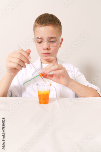 white boy cooks orange lime on a white table. The boy is doing a chemistry lesson
