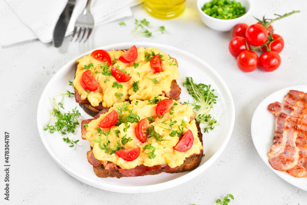 Scrambled eggs with microgreen, bacon and tomato slices on bread Scrambled eggs with microgreen, bacon and tomato slices on bread