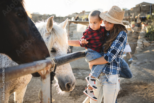 Mother with little son having fun a horse at farm ranch - Focus on kid face photo