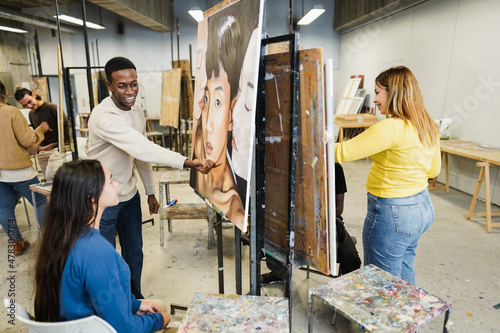 Multiracial students painting inside art room class at university - Focus on african guy face photo