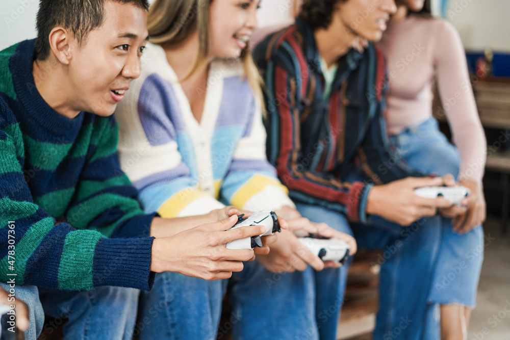 Obraz premium Multiracial young friends having fun playing video games at home - Focus on asian boy hand