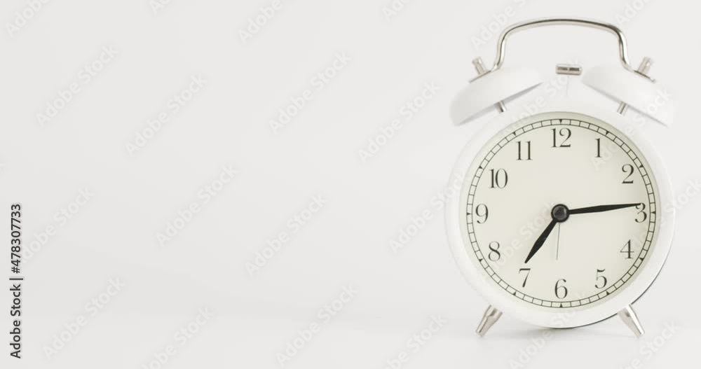 Time lapse White alarm clock shows the time at 7 o'clock. The clock shows the elapsed time on the white background. Time lapse White alarm clock shows the time at 7 o'clock. The clock shows the elapsed time on the white background.